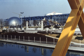 Вид на парк Ля Виллетт, открывающийся
с пешеходного перехода: Музей науки,
техники и промышленности (это здание
существовало до постройки парка и было
сохранено без изменений), зеркальная
сфера кинотеатра «Жеод».